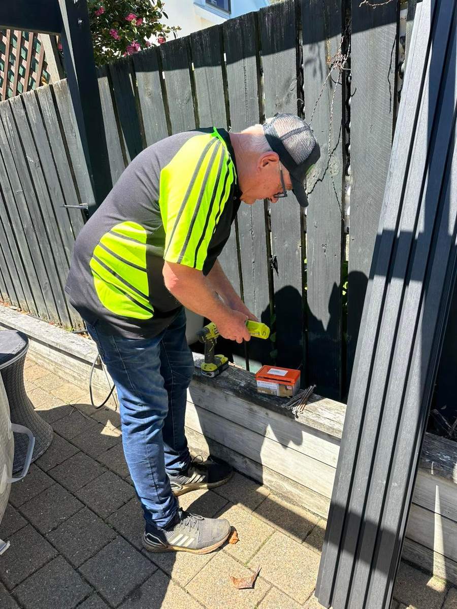 Team member drilling composite fencing into place